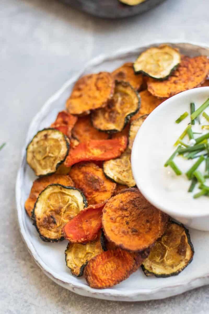 porcja chipsów warzywnych w miseczce miseczka pełna kolorowych chipsów warzywnych obok szklanki lemoniady
