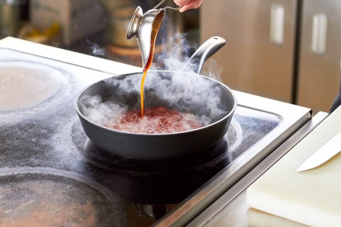 Sauce boat pouring on pan.