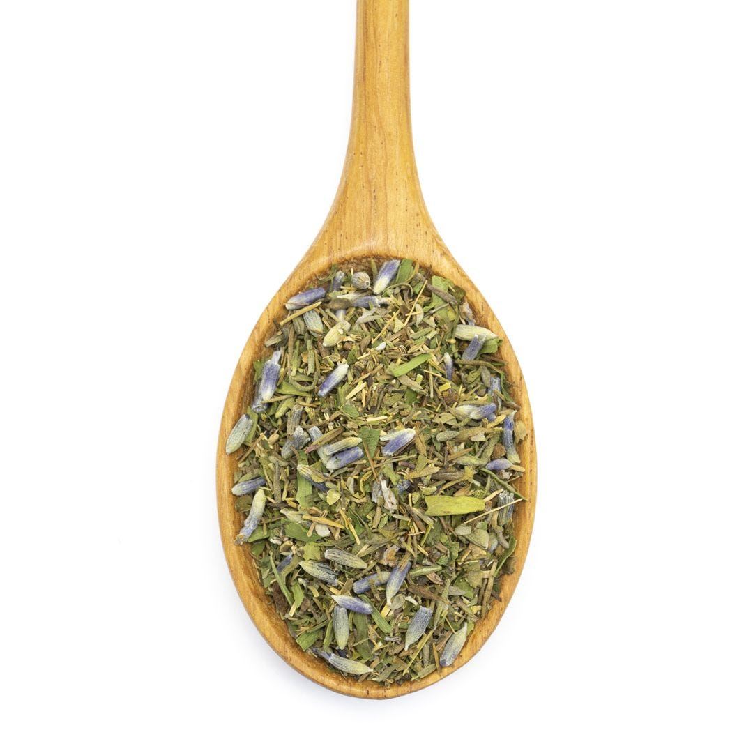 Młynek ceramiczny napełniony ziołami prowansalskimi obok potrawy