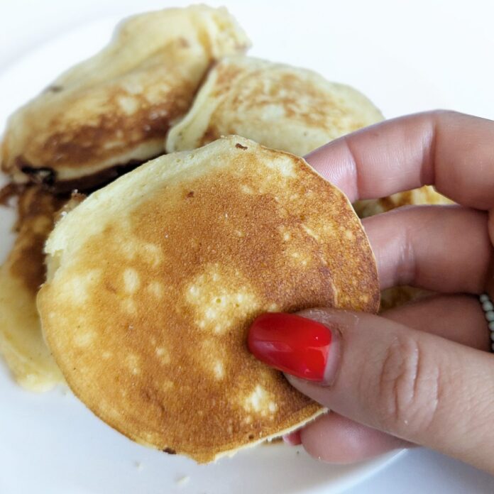 Stos puszystych złocistych naleśników bezglutenowych na talerzu z malinami i miętą