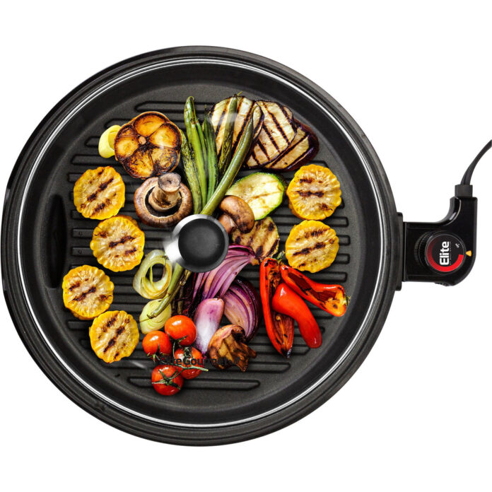 młoda kobieta grillująca warzywa i kurczaka na grillu elektrycznym w kuchni