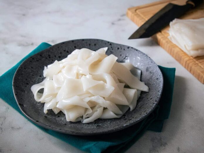 parujący talerz z gotowym makaronem ryżowym i świeżymi ziołami